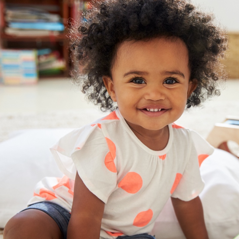 A photo of a smiling toddler with a big halo of curly hair